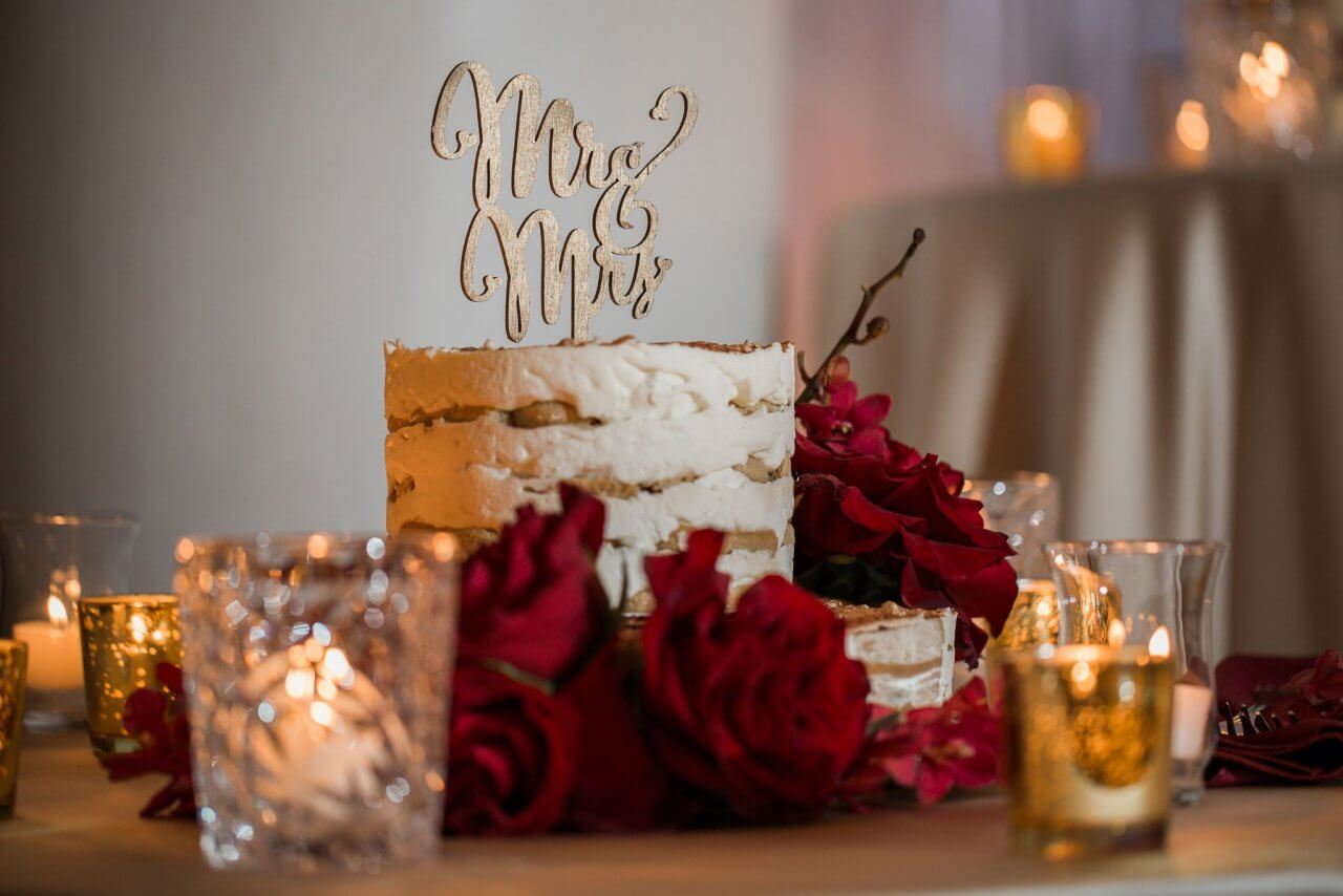 white and gold naked wedding cake with red flowers
