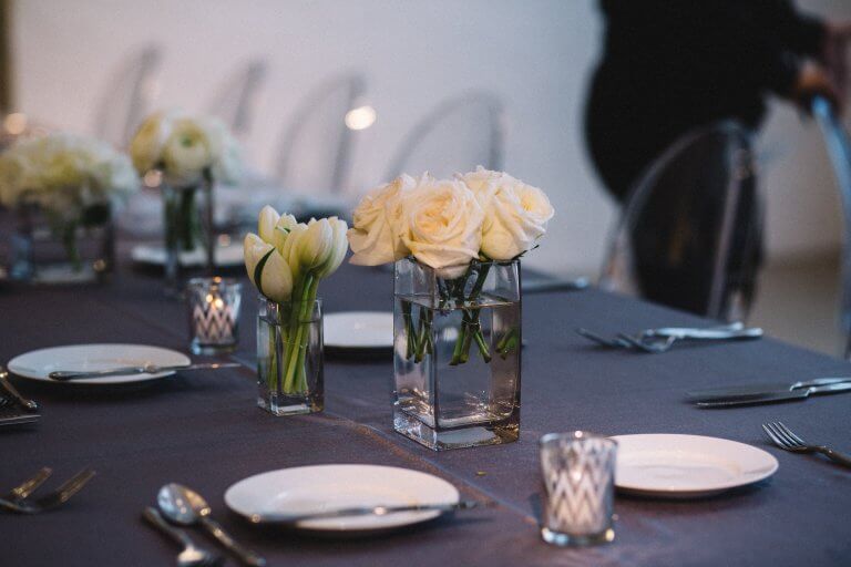 white roses and tulips in glass vase on blue table