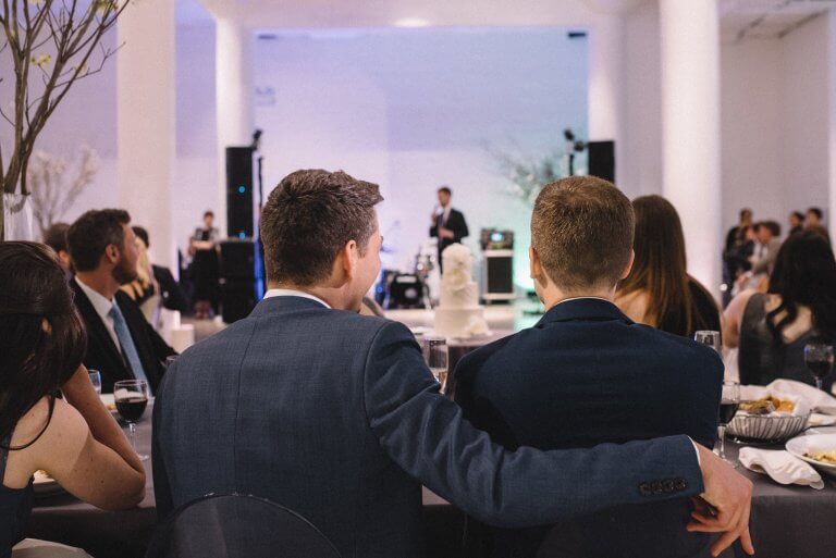 grooms in navy suite at head table backs turned