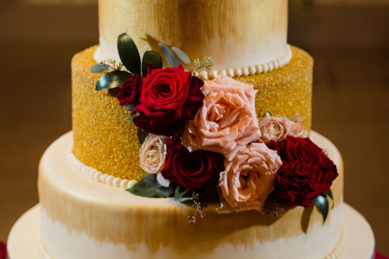 red and pink roses on gold wedding cake at chez wedding venue chicago