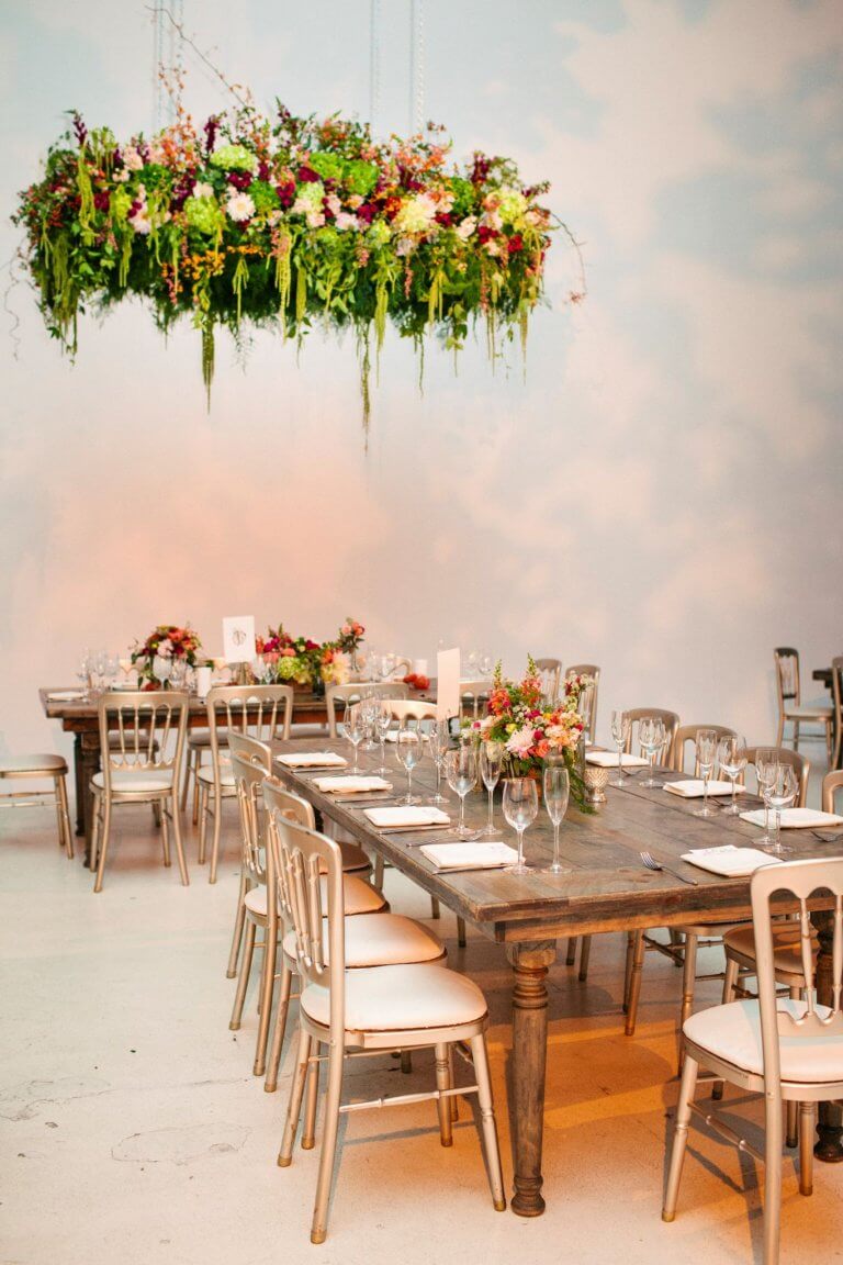 wodden wedding tbales with overhead colorful hanging florals