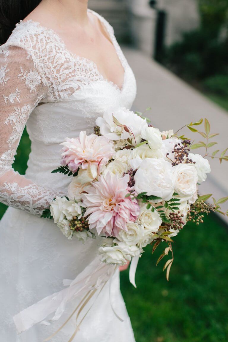 bride in lace dress holding white and pink floral bouquet