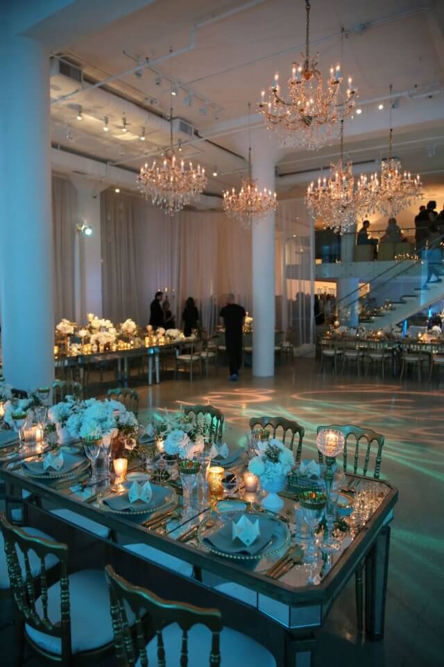 blue and gold wedding reception with mirrored tables and golden chandeliers