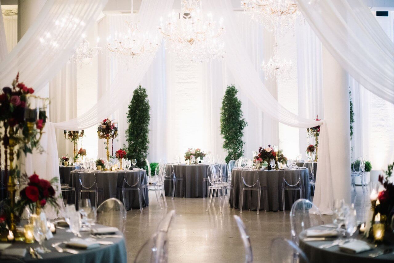 winter wedding with white drapery hanging from celing silver tablecloths and greenry