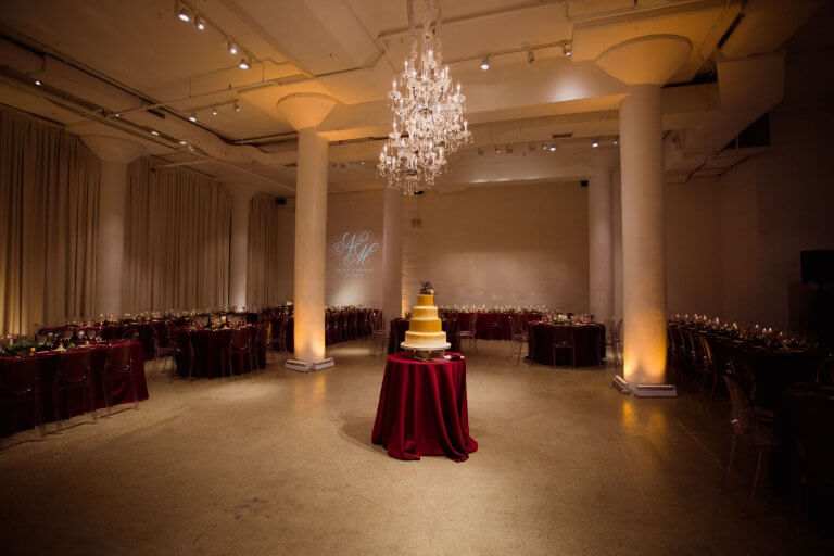 gold and burgundy wedding reception with four tier wedding cake under crystal chandeliers