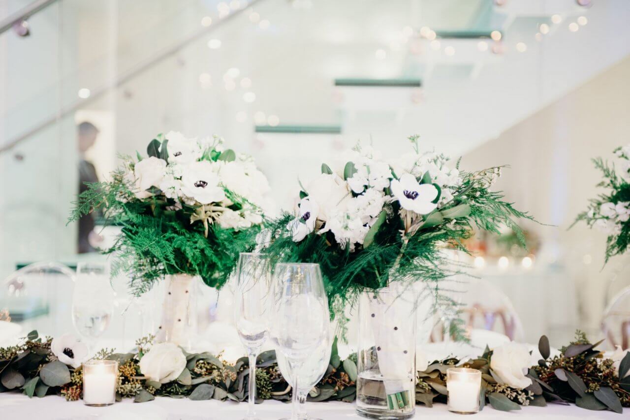 magnolia runner on white head table with white and green bouquets