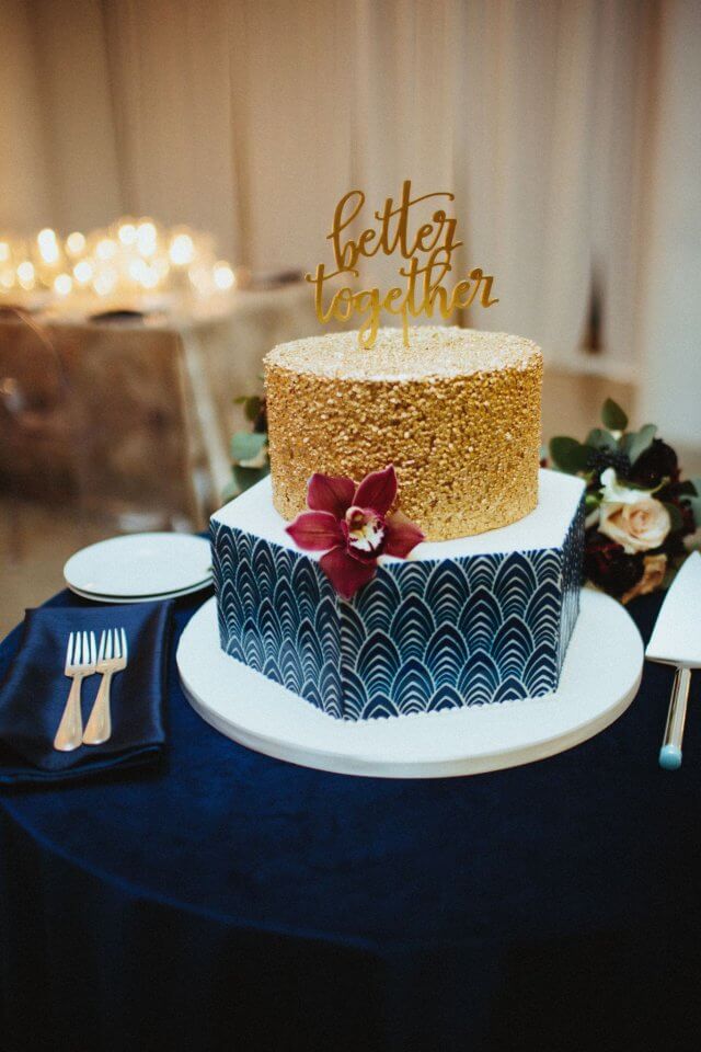 gold and navy wedding cake with burgundy flower