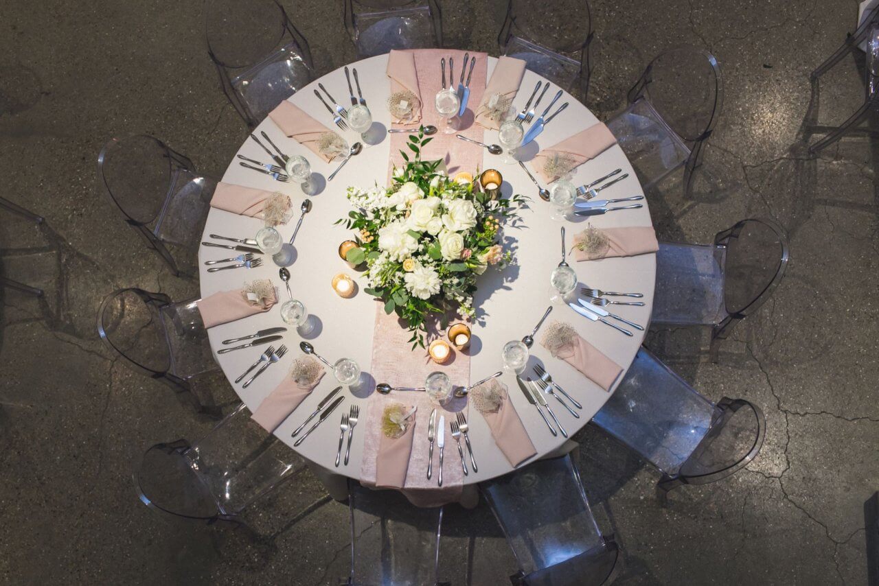 white round table with pink napkins and large floral arrangement