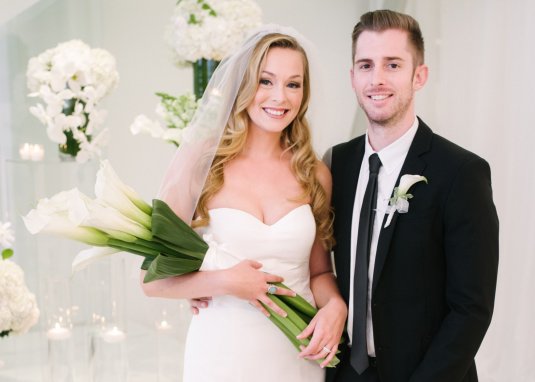 bride and groom smile in white event space