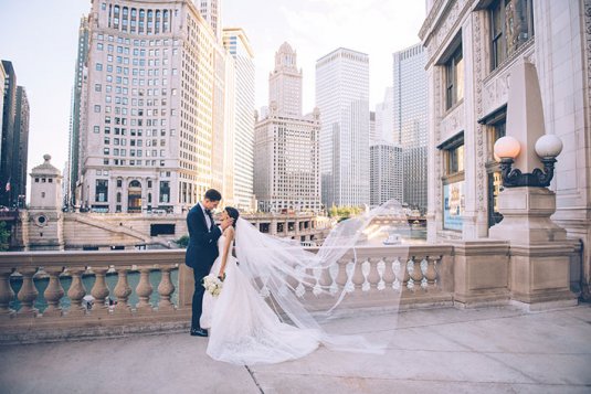 bride and groom pose in front of chicago river