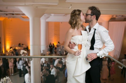 bride and groom kiss on chez stairs with amber lit background