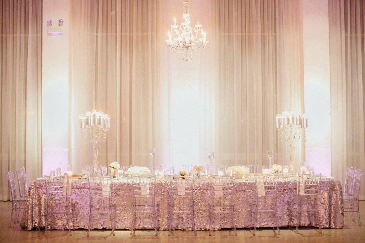 silver sequin head table with lucid candles and overhead chandeliers