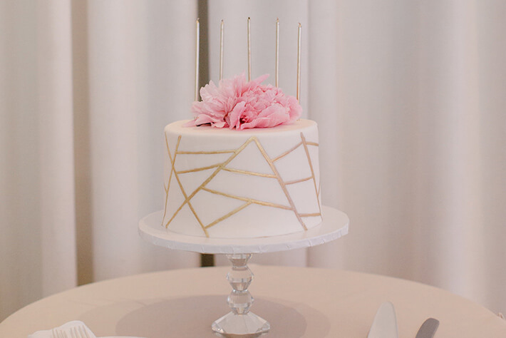 white and gold geometric wedding cake with pink flowers