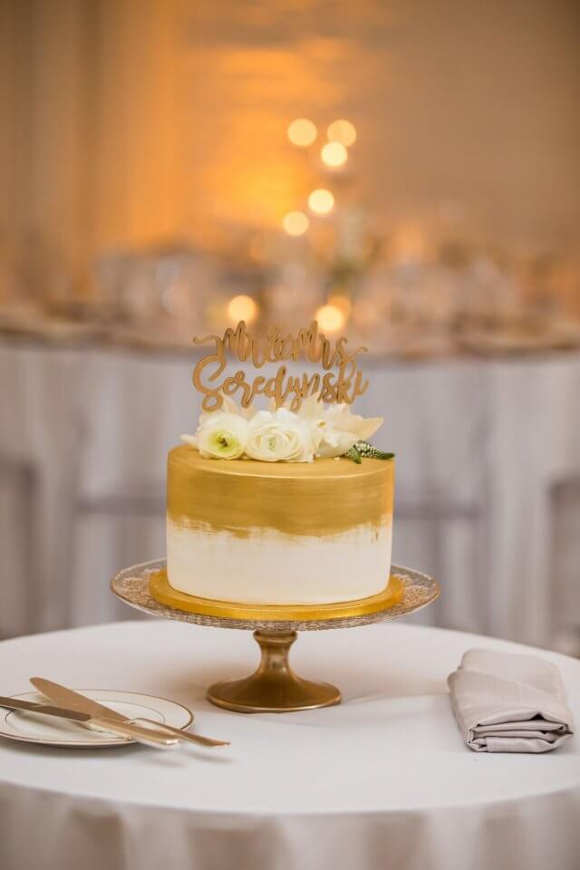 white and gold painted wedding cake on white table