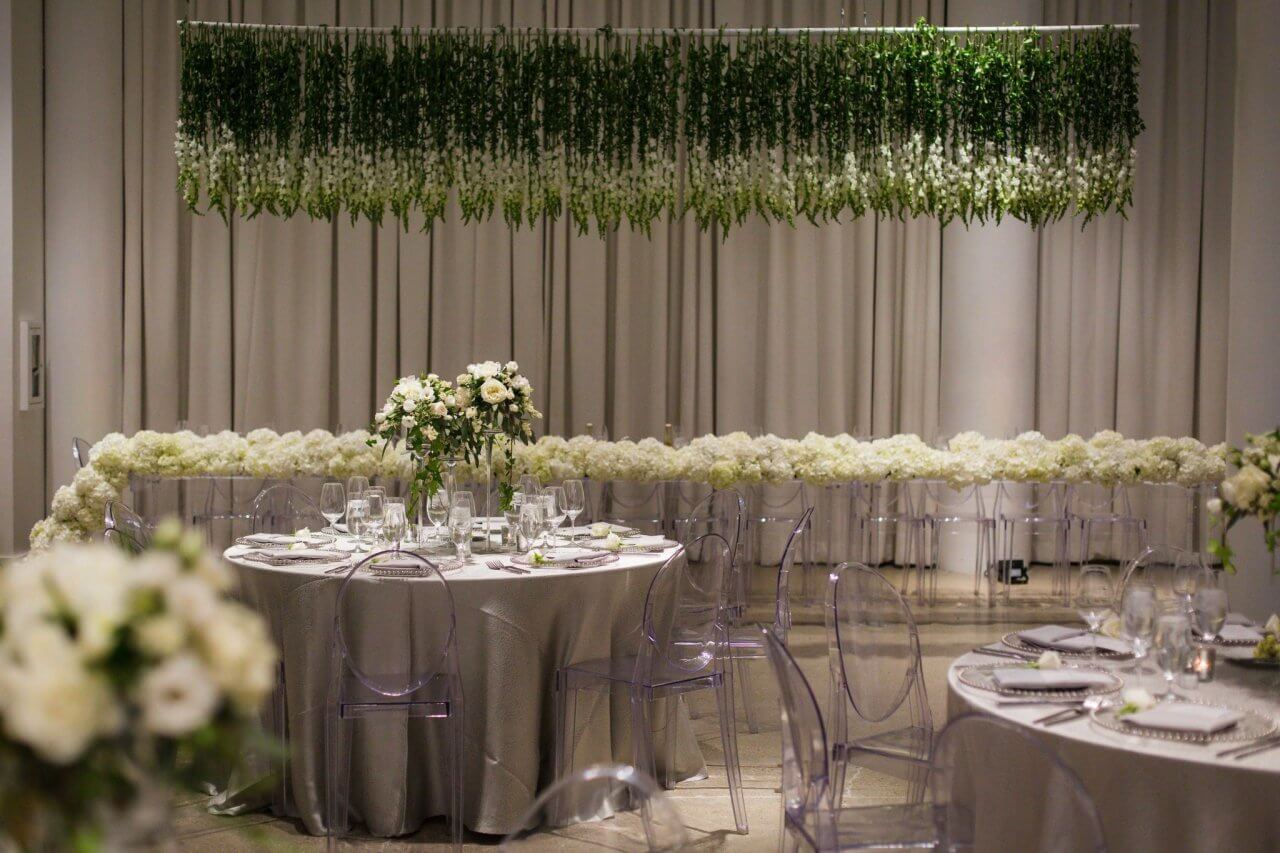 white and green floral reception with hanging green and white floral piece