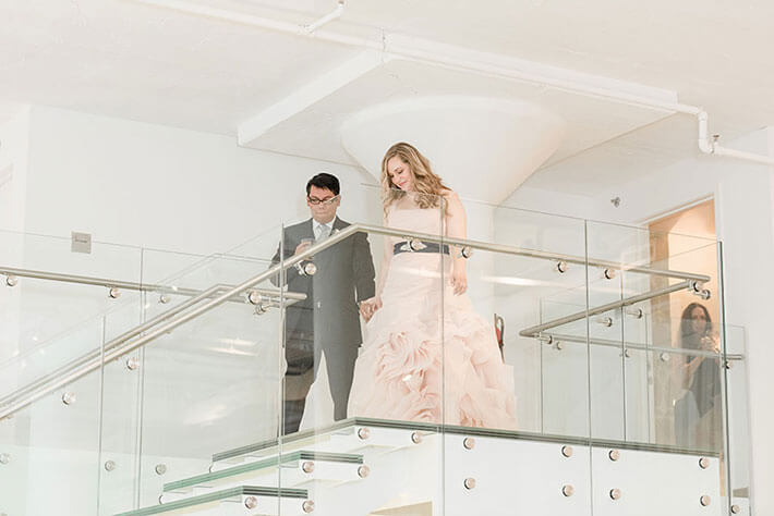 bride in pink dress and groom walk down chez wedding staircase