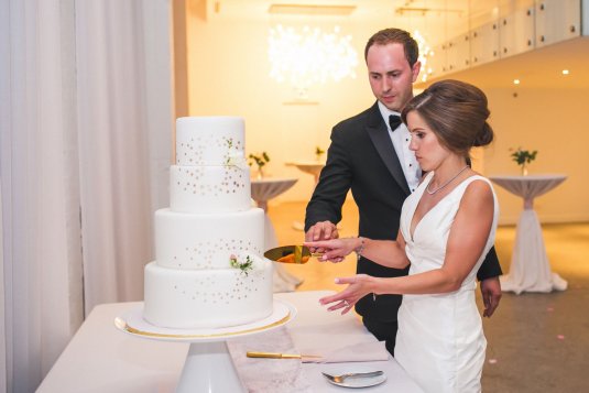 four tier white and gold wedding cake in gold lit space