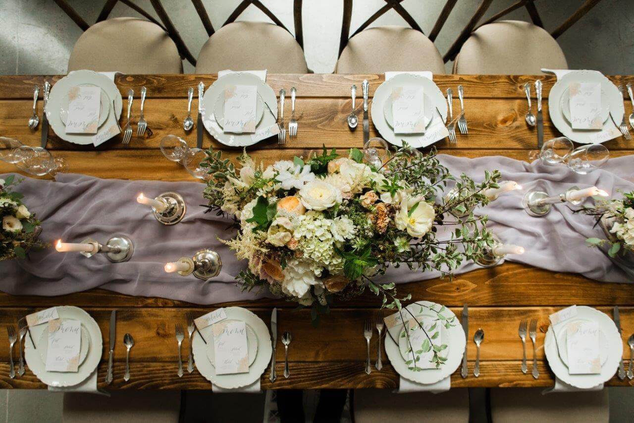 wooden farm table with purple runner and white place settings