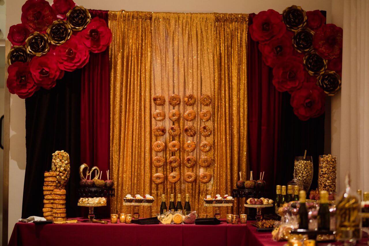 wedding sweets table with gold sequin backdrop and donuts and candy