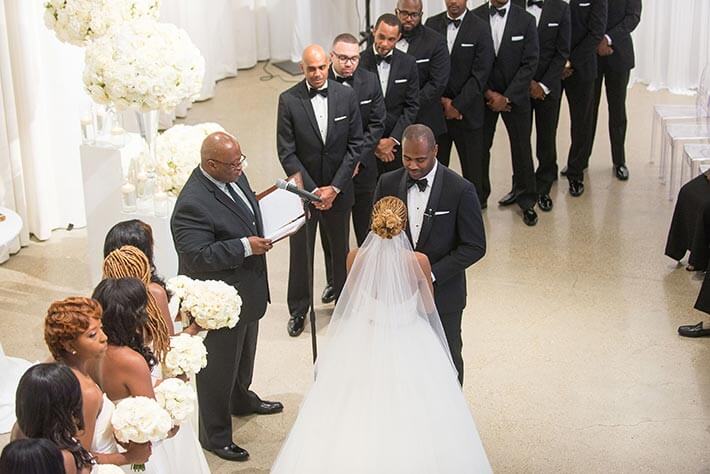 bride and groom hold hands at alter at white modern wedding