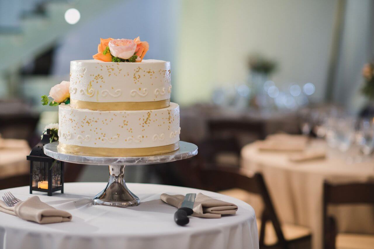 gold white and peach wedding cake on white table