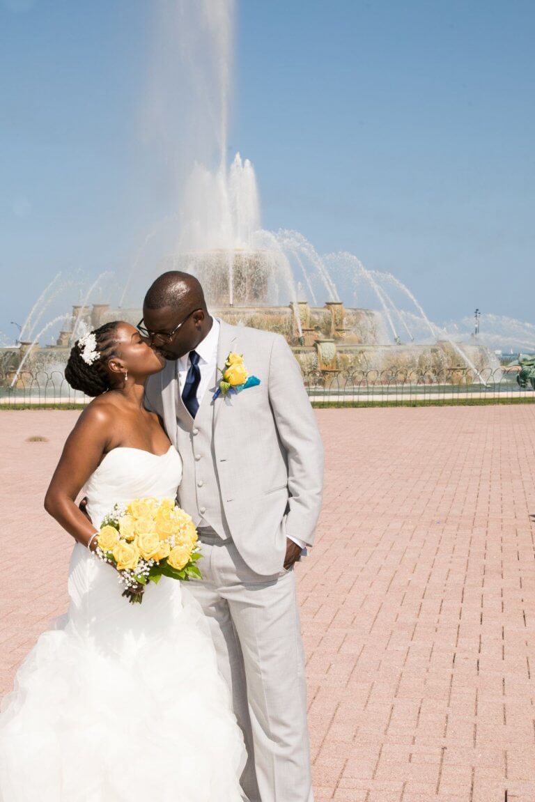 bride hold yellow roses and kisses groom at grant park fountain