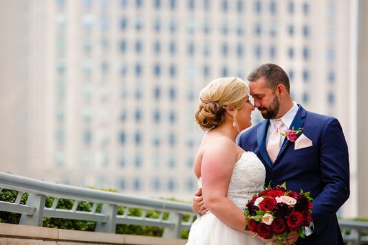 bride and groom holding red bouquet of roses outisde in chicgao