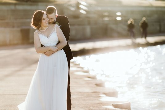 bride and groom hug on the edge of the river