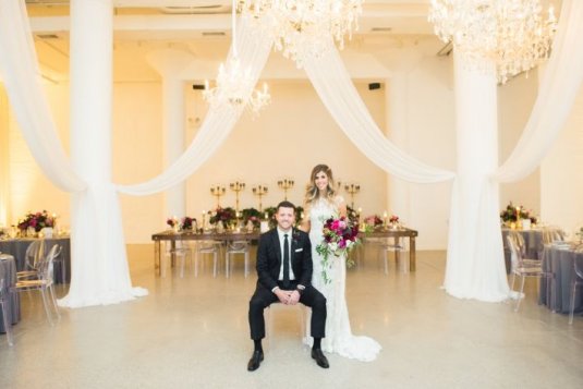bride and groom pose in the middle of rustic wedding reception