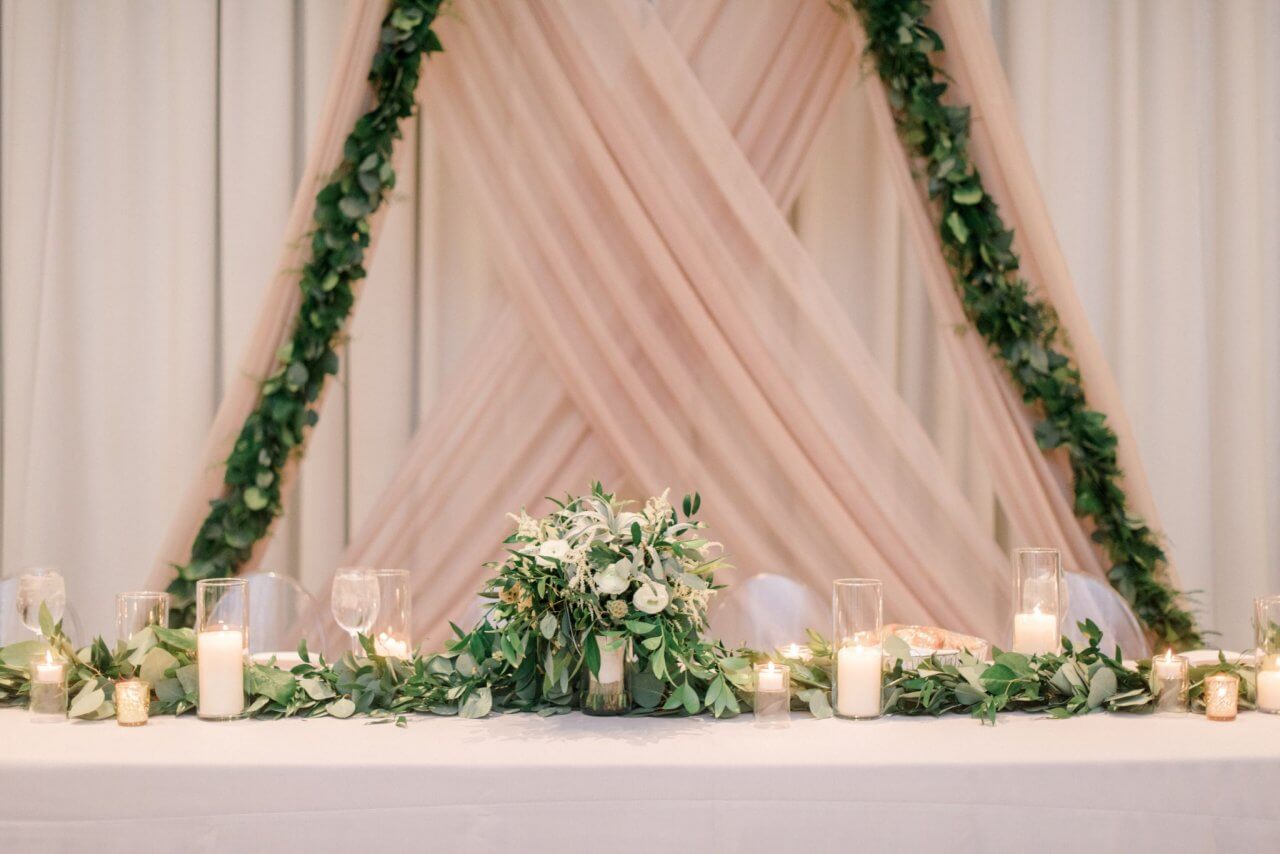 blush drapery behind head table with greenery