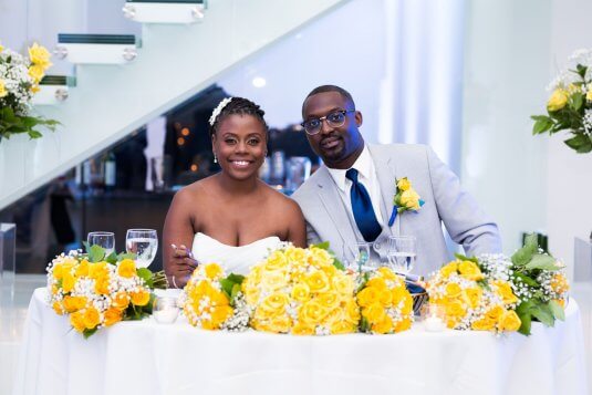 bride and groom smile at yellow rose head table