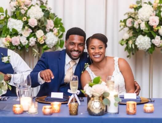 bride and groom smile at navy head table
