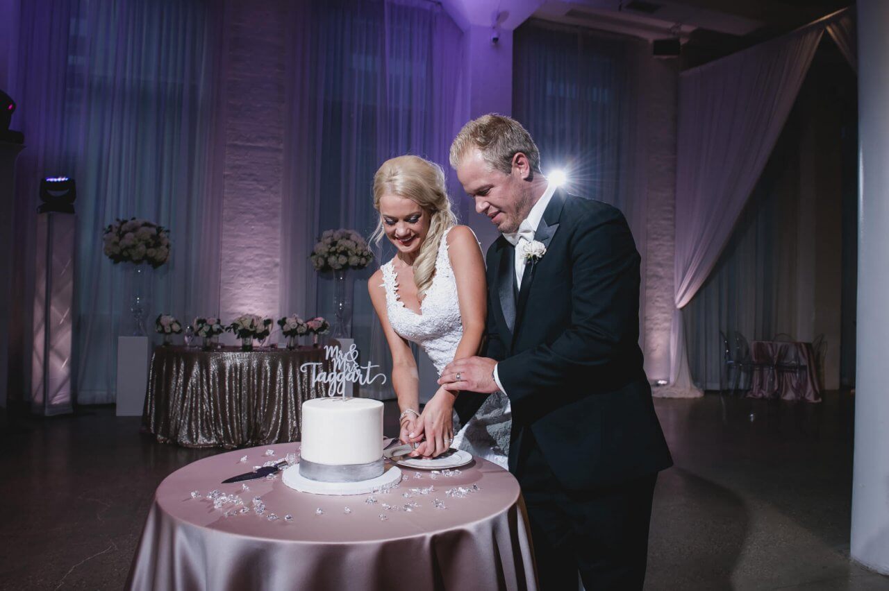 bride and groom cut the cake in purple theme wedding reception