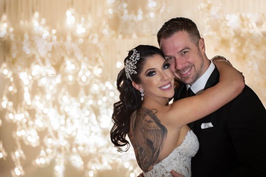 bride and groom smile and hug infront of chandelier