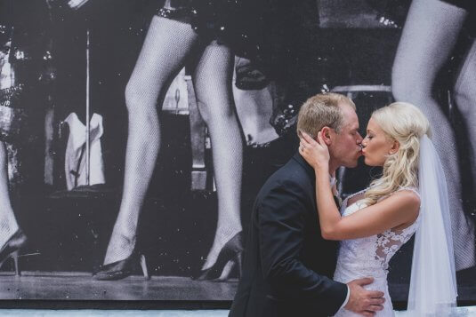 bride and groom kissing in front of chez mural