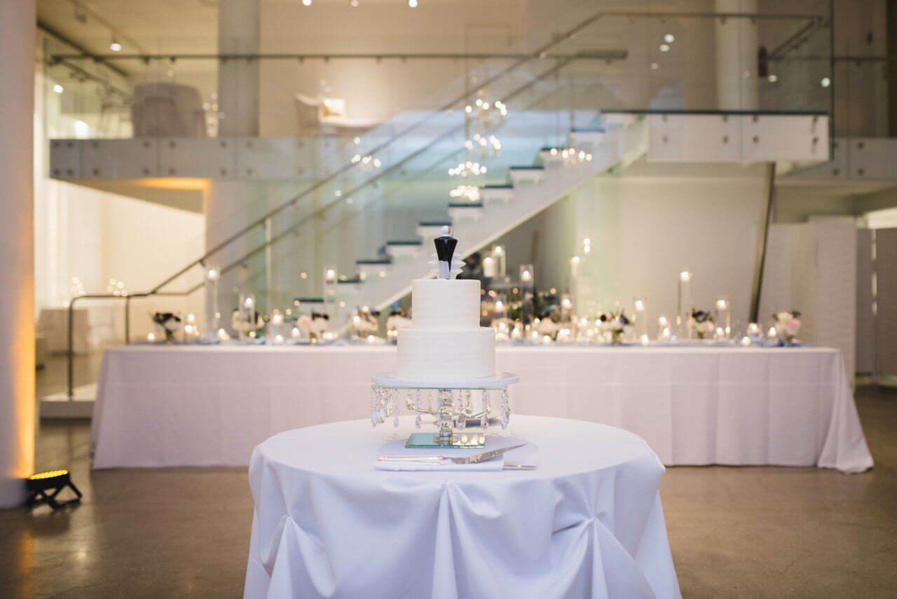 two tier wedding cake on light blue table with chez glass stairs in background