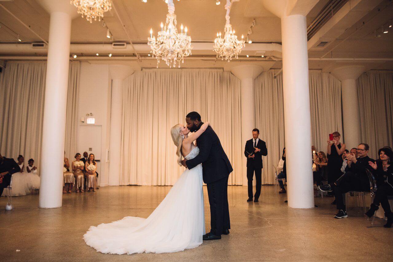 bride and groom kiss under golden chandeliers in chez wedding venue