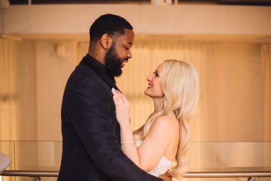 bride and groom smile at each other in chez with golden background