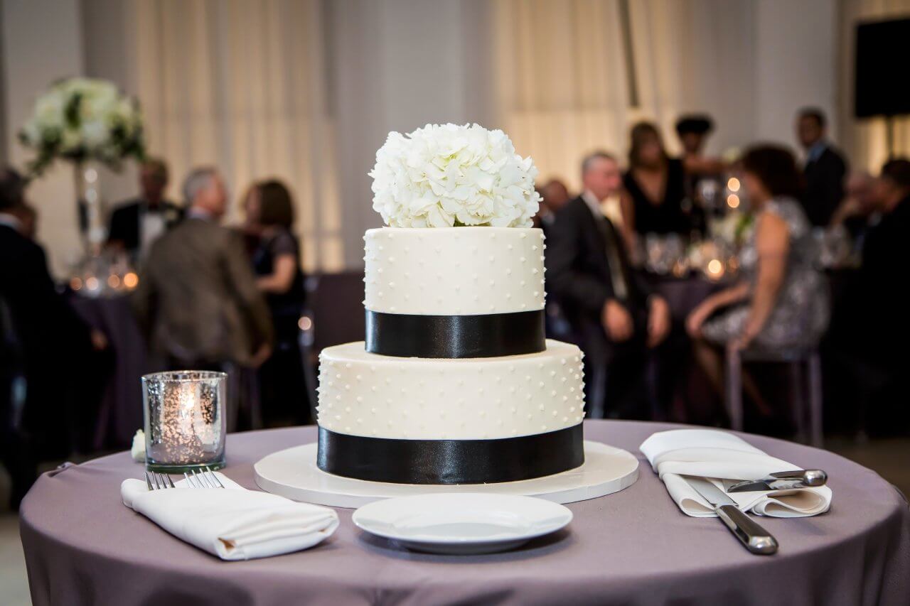 white and black wedding cake with floral topper on purple table