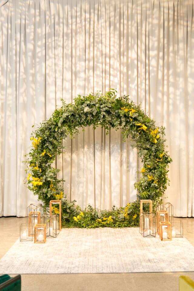green and yellow floral ceremony circle with gold candles and white carpet