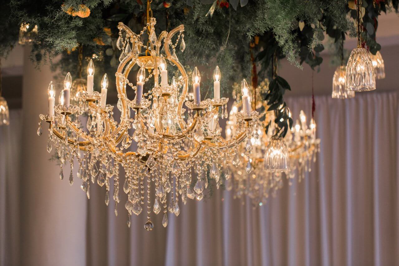 gold chandeliers hanging from greenery on celing