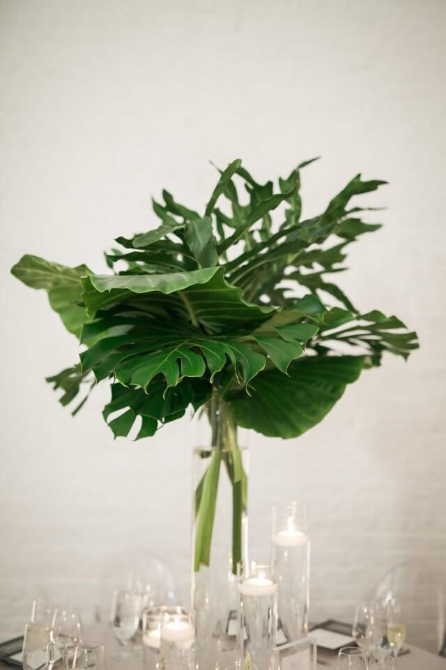 large green palm leaves in glass vase on round wedding table